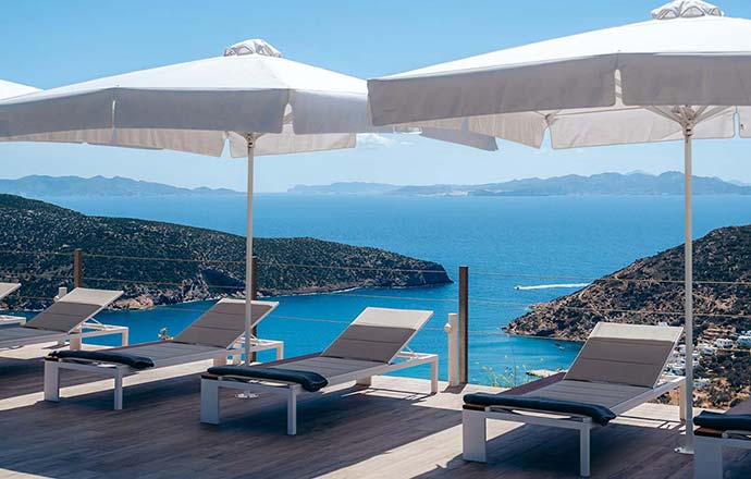 Ξαπλώστρες στο χώρο της πισίνας με θέα στη θάλασσα